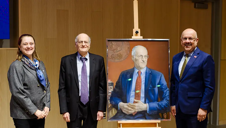 Noebl Laureate Thomas J. Sargent stands with a painted portrait of himself, with Tepper Dean Isabelle Bajeux-Besnainou standing on his left and CMU President Farnam Jahanian standing to the right of the portrait