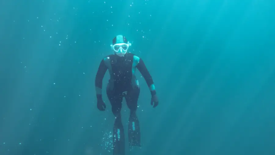 A freediver in a wetsuit swims underwater