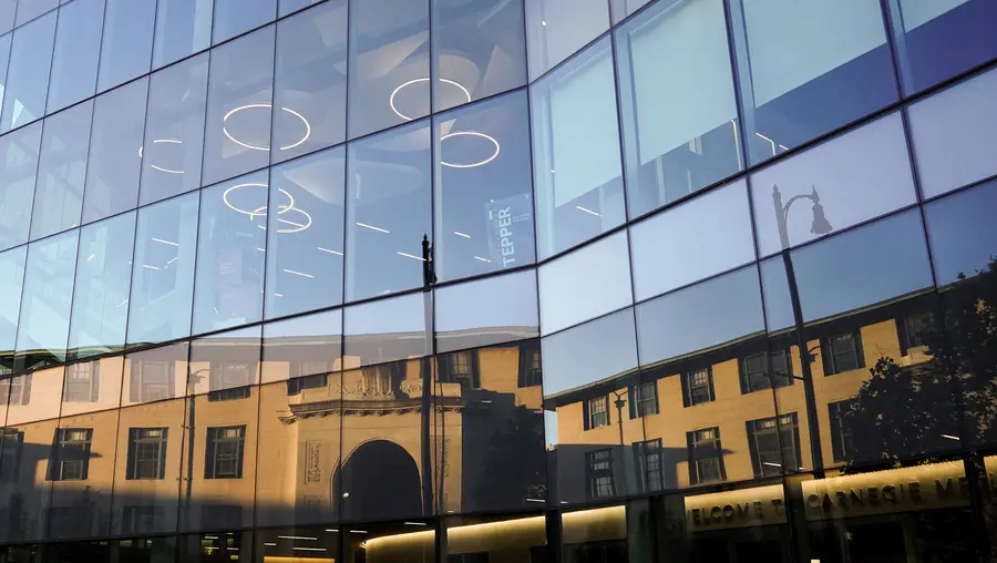 Hamburg Hall reflected in the Tepper Building's windows.