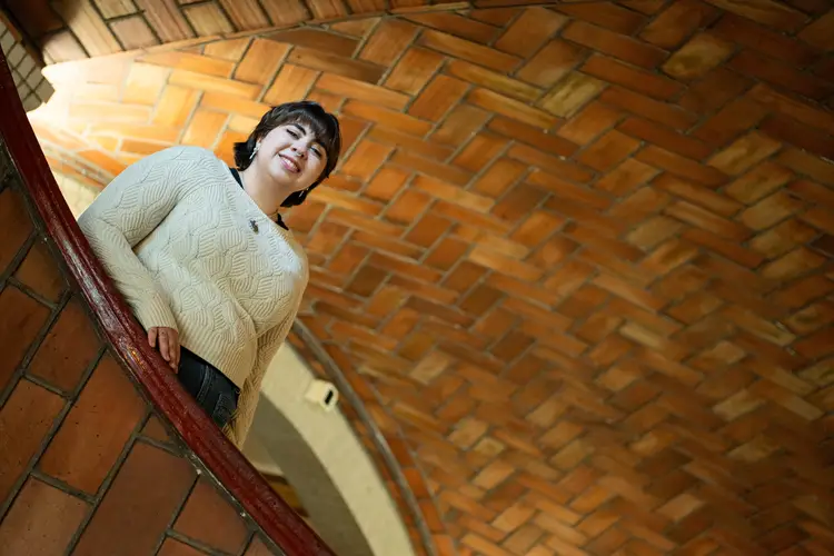 A smiling woman peers down from the stairwell in Baker Hall